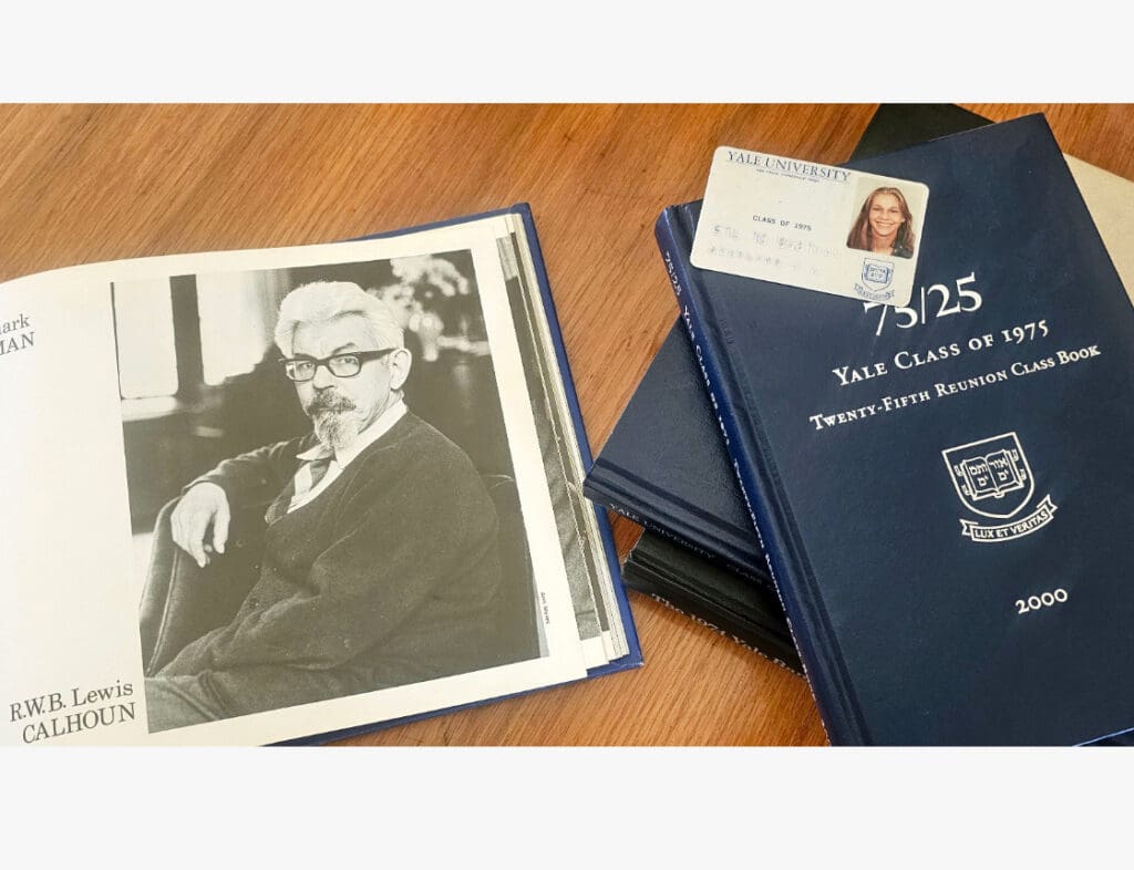 Open book with a black-and-white portrait, Yale reunion books, and an ID card on a wooden table.