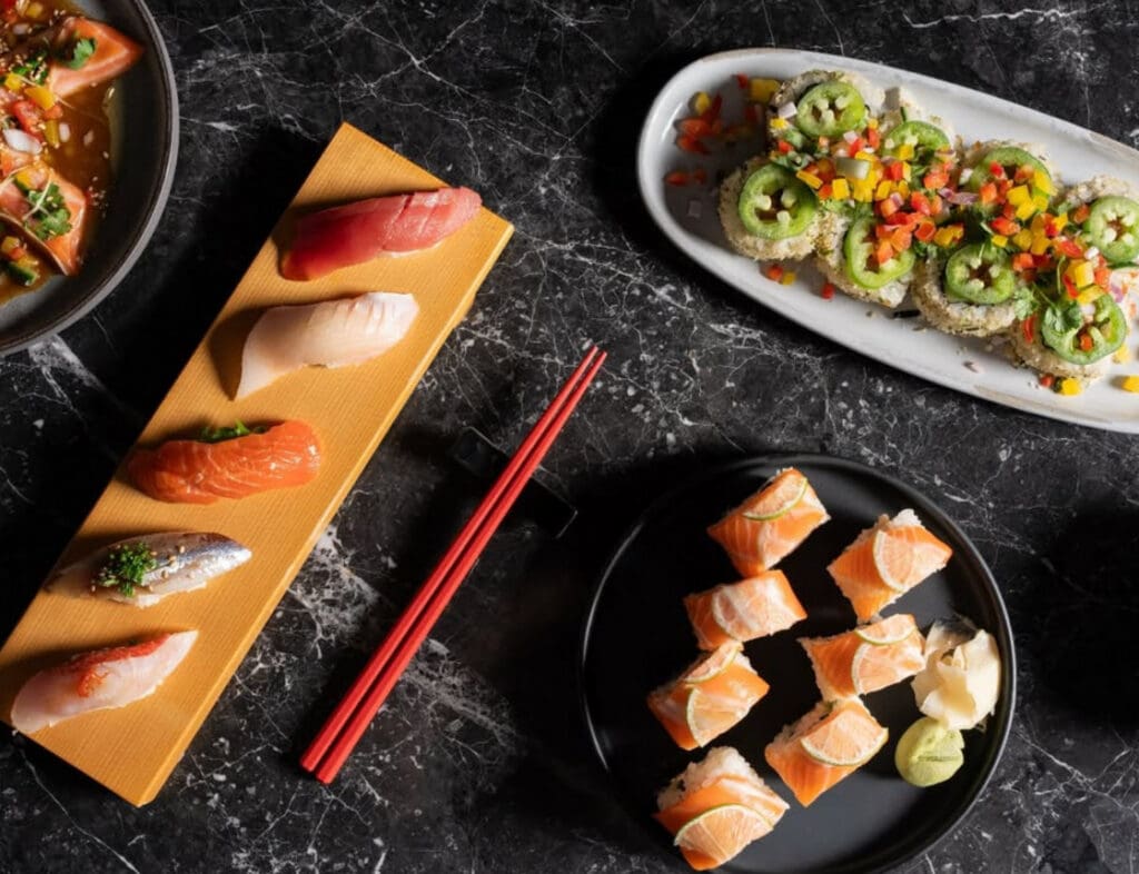A plate of sushi and chopsticks on a marble table.