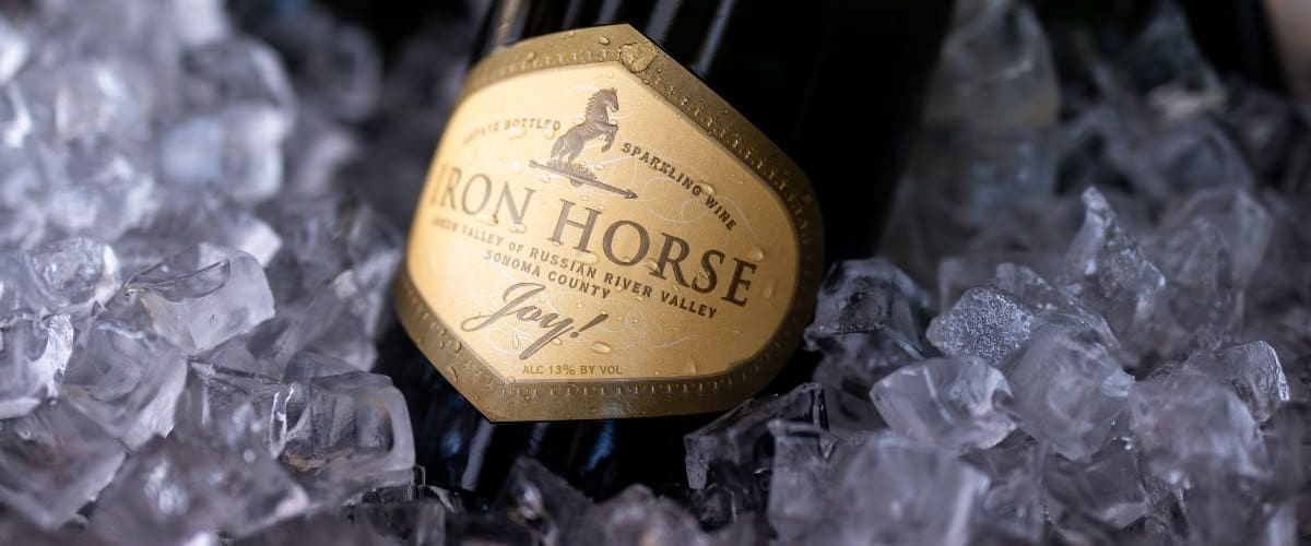 A bottle of Iron Horse sparkling wine resting on ice cubes.