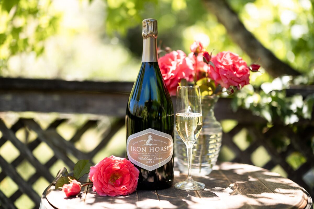 a bottle of wedding cuvee with a flute half filled with champagne and pink flowers