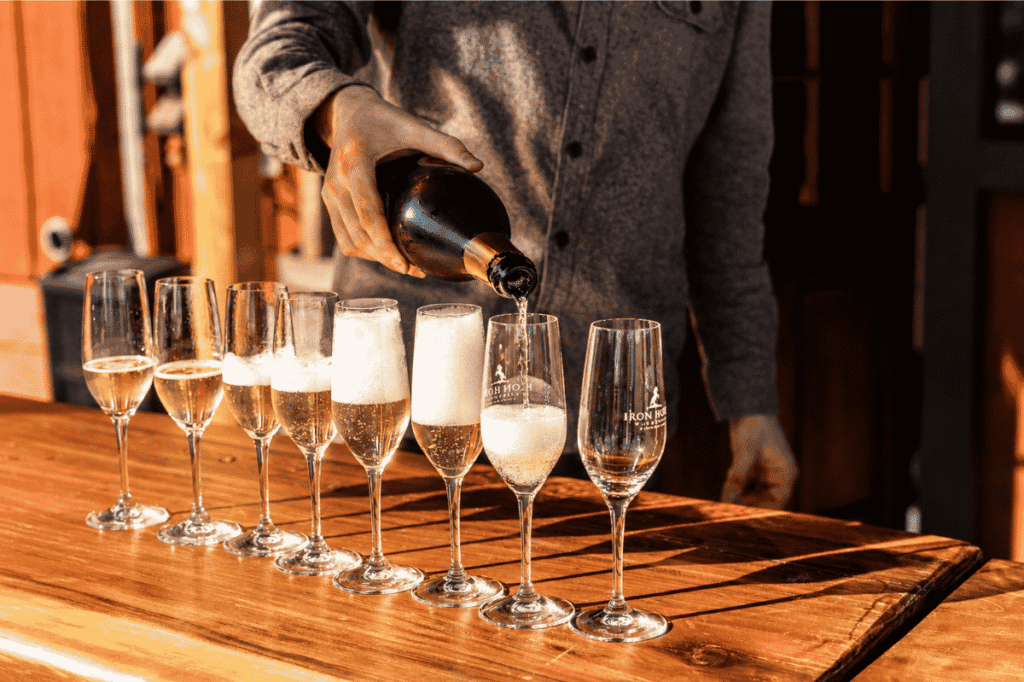 A lineup of flutes being filled with Sparkling wine