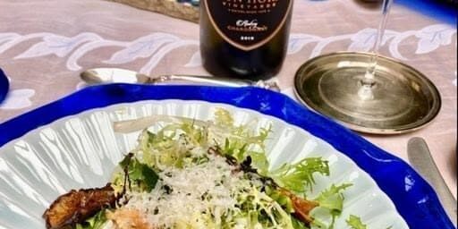 A plate of salad with mushrooms next to a bottle of Iron Horse wine and a glass of white wine.