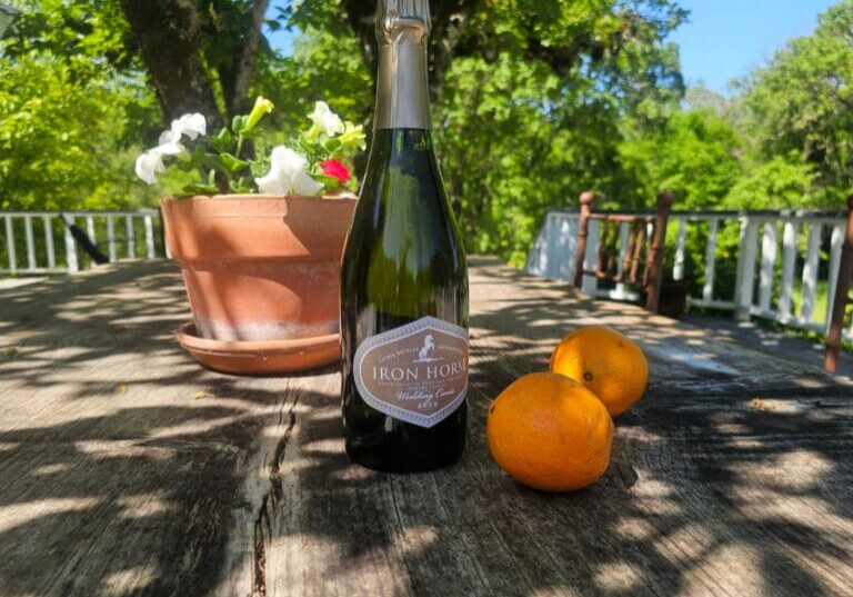 A bottle of wine and oranges on a table.