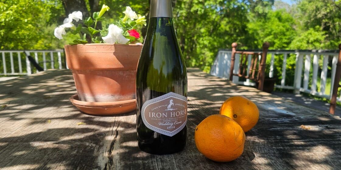 A bottle of wine and oranges on a table.