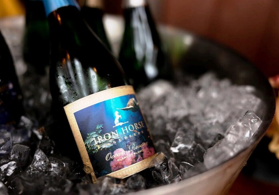 A bottle of Iron Horse sparkling wine chilling in a bucket filled with ice.